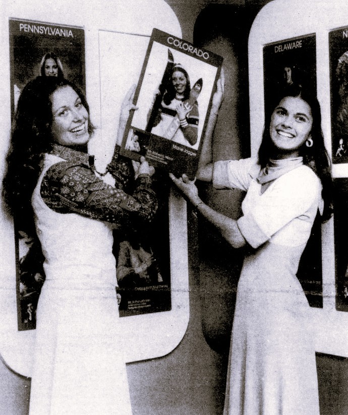 Two young women hang a promotional photograph.
