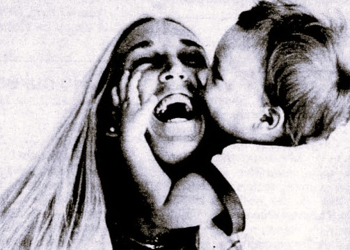 A woman laughs while her baby kisses her face.