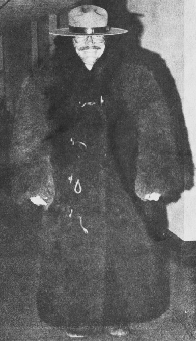 A man wears a ranger hat and a giant fur coat.