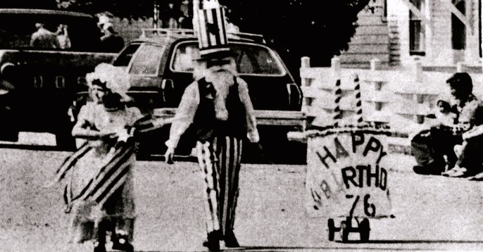 A boy dressed as Uncle Sam and a girl in colonial dress walk in a U.S. Bicentennial parade.