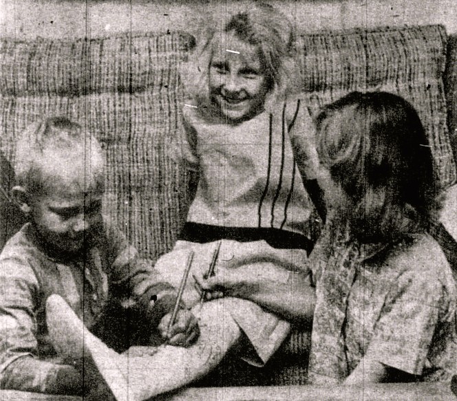 Two children sign a girl's leg cast.