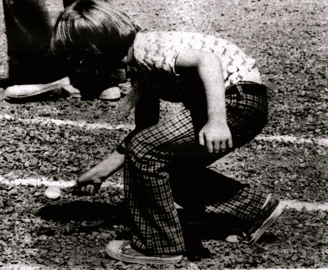 A child balances a golf ball on a spoon.