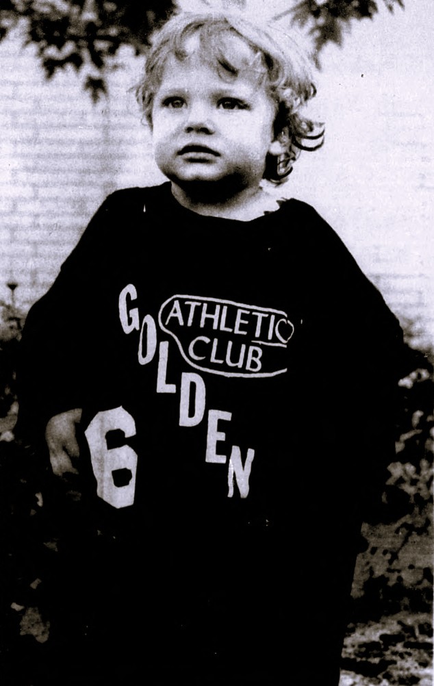 A small child wears an oversized shirt.