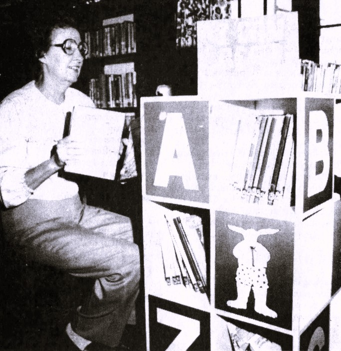 A librarian shelves books on a spinning display.