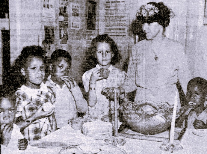 A woman serves punch and cookies to five children.
