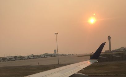 View from inside an airplane of hazy skies making the sun look orange.