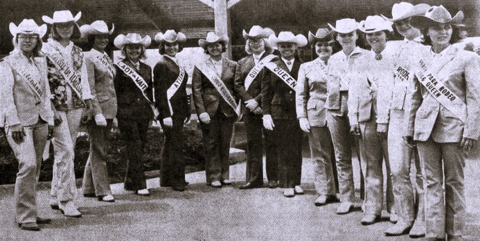 A group of rodeo queens and their attendants pose wearing Western outfits and pageant sashes.