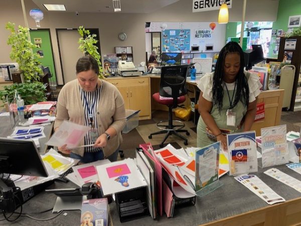 Two women organizing papers and colored game pieces