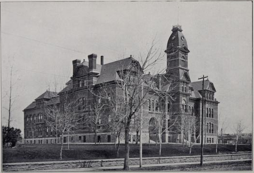 black and white photo of elaborate brick and stone building with a tall front tower