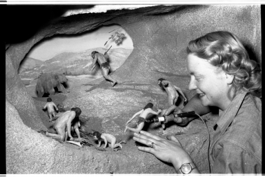 woman arranging caveman diorama