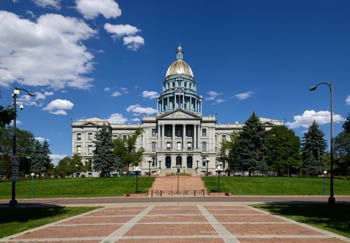 A red slate path and stairs leading up to large white building with a golden dome.