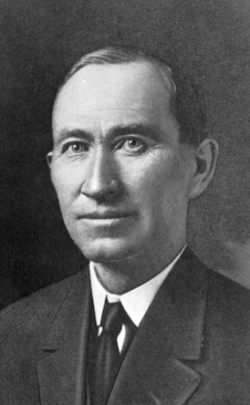 A black and white photographic headshot of Governor Ammons, wearing a black suit and tie and a white shirt.