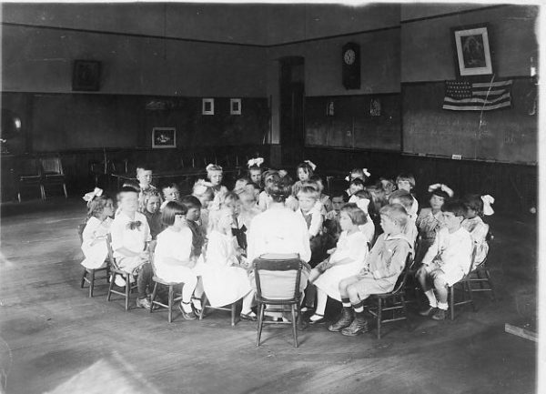 A first grade class sits in concentric circles around their teacher, assumed to be Helen Lawrence since she was the only first grade teacher at Arvada School until 1926 or 1927.