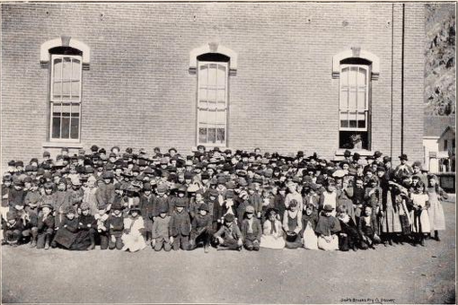 large group of children posed outside brick building