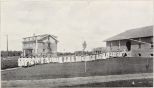 black and white photo of students lined up in front of building