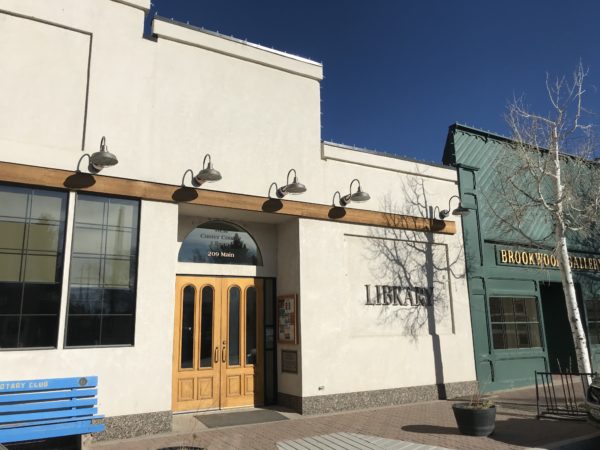Entrance to West Custer County Public Library, with double doors and lights overhanging the sidewalk.