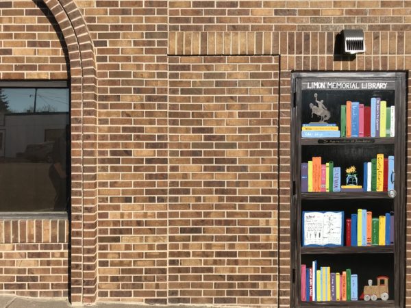 The side door of the Limon Public Library, painted to look like a book shelf with colorful titles on display.