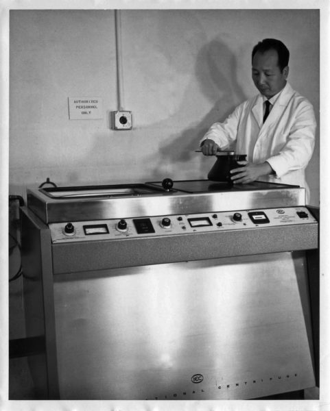 man in a lab coat next to a large machine