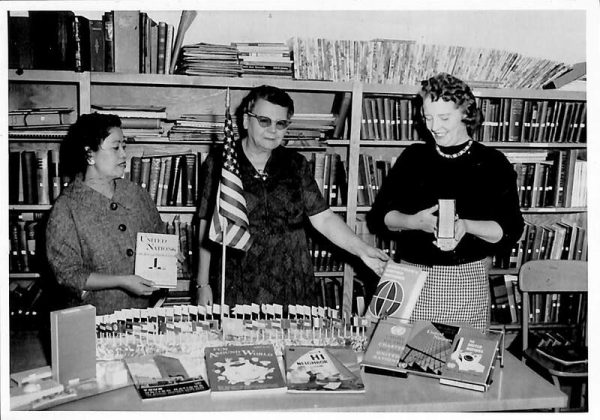 Three librarians pose with books at the Arvada Library