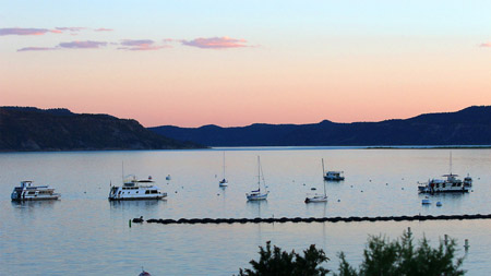 Two sailboats and two houseboats on Navajo Lake at sunset.