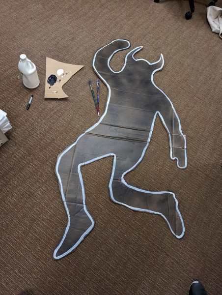 cut out of the body outline of a troll with horns made to look like a crime scene 