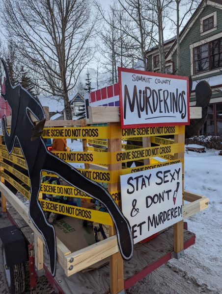 signs and crime scene tape and a cardboard cut out of a troll made to look like a chalk outline of a dead body 