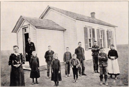 students and teachers outside small wooden building