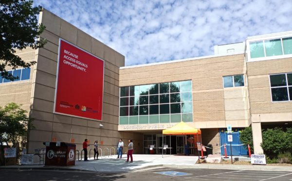 Entrance to the Longmont Public Library, showing curbside service delivery and large sign reading "Because access equals opportunity."