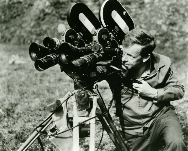 man looking through eyepiece of movie camera