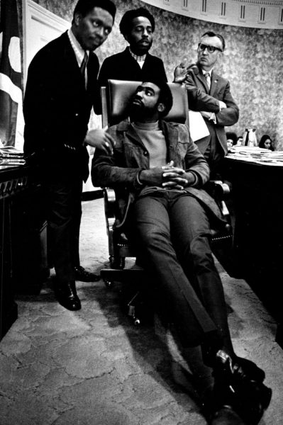 Picture of Lauren Watson in a chair surrounded by three men in Denver City Hall