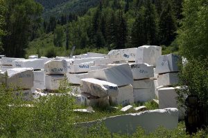 large blocks of uncut marble amidst green trees and bushes