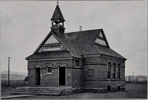 black and white photo of small brick building with bell tower