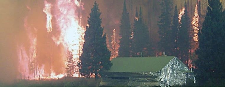 fire near a building that appears to be wrapped in aluminum foil