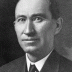 A black and white photographic headshot of Governor Ammons, wearing a black suit and tie and a white shirt.