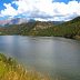 The Paonia Reservoir with a grassy hillside and mountains in the background.