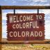 A large wooden sign with white letters reading "Welcome to Colorful Colorado."