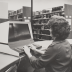 A woman works on an early library computer terminal.