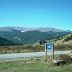 A paved highway cuts through a high alpine landscape with the columbine sign denoting a Scenic and Historic Byway.