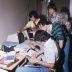 4 high school boys gather around a table with a computer and books.