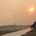 View from inside an airplane of hazy skies making the sun look orange.