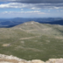 The paved byway winds through a treeless alpine tundra with mountain peaks in the background.